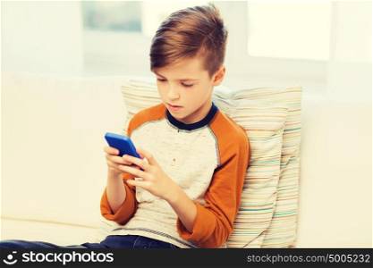 leisure, children, technology, internet communication and people concept - boy with smartphone texting message or playing game at home. boy with smartphone texting or playing at home