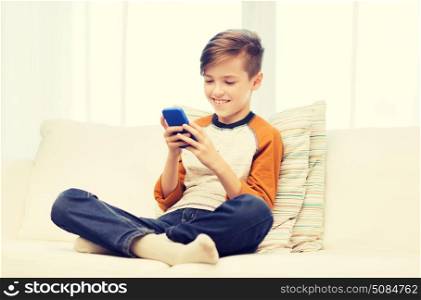 leisure, children, technology, internet communication and people concept - smiling boy with smartphone texting message or playing game at home. boy with smartphone texting or playing at home. boy with smartphone texting or playing at home