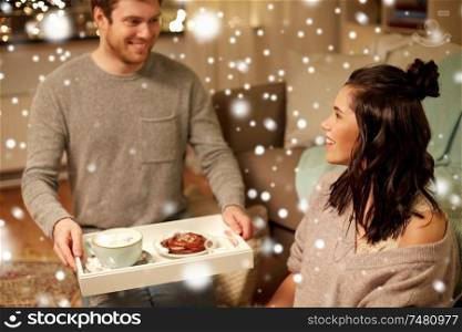 leisure, christmas and people concept - happy couple with food on tray at home over snow. happy couple with food on tray at home