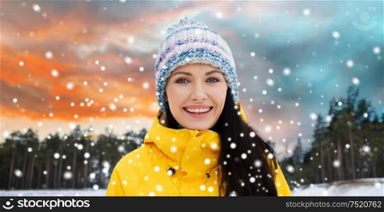leisure, clothing and people concept - happy young woman over winter forest background. happy young woman in winter clothes outdoors