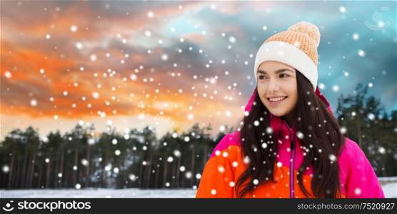 leisure, clothing and people concept - happy young woman over winter forest background. happy young woman in winter clothes outdoors