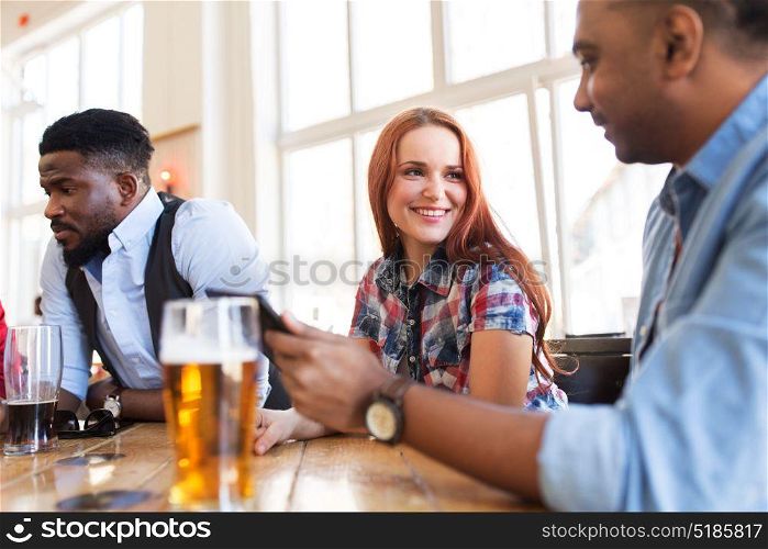 leisure, communication and people concept - group of happy international friends with tablet pc computer drinking beer and talking at bar. happy friends with tablet pc drinking beer at bar