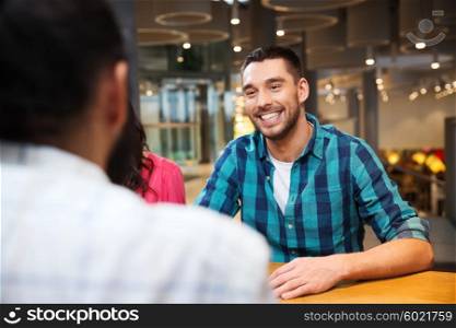 leisure, communication and people concept - happy smiling man meeting with friends at restaurant