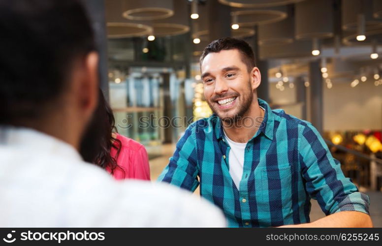 leisure, communication and people concept - happy smiling man meeting with friends at restaurant