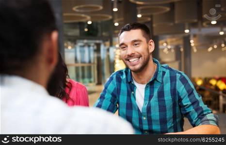leisure, communication and people concept - happy smiling man meeting with friends at restaurant