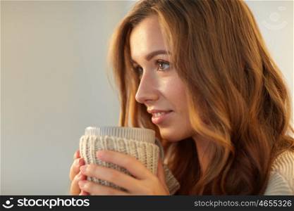leisure, drink, winter and people concept - close up of happy young woman with cup of coffee or tea at home