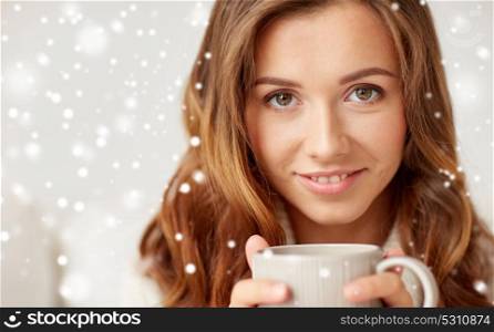 leisure, drink, winter and people concept - close up of happy young woman with cup of coffee or tea over snow. close up of happy woman with coffee cup over snow