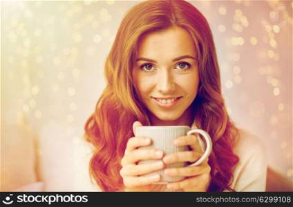 leisure, drink, winter and people concept - close up of happy young woman with cup of coffee or tea at home. close up of happy woman with coffee cup at home