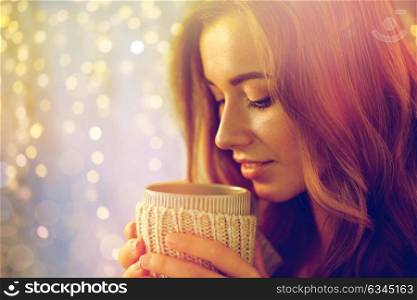 leisure, drink, winter and people concept - close up of happy young woman with cup of coffee or tea at home. close up of happy woman with tea or coffee cup