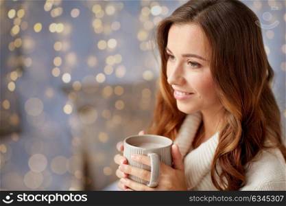 leisure, drink, winter and people concept - happy young woman with cup of coffee or cocoa at home. happy woman with cup of cocoa or coffee at home