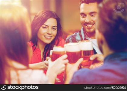 leisure, drinks, celebration, people and holidays concept - smiling friends drinking beer and clinking glasses at restaurant or pub. friends drinking beer and clinking glasses at pub