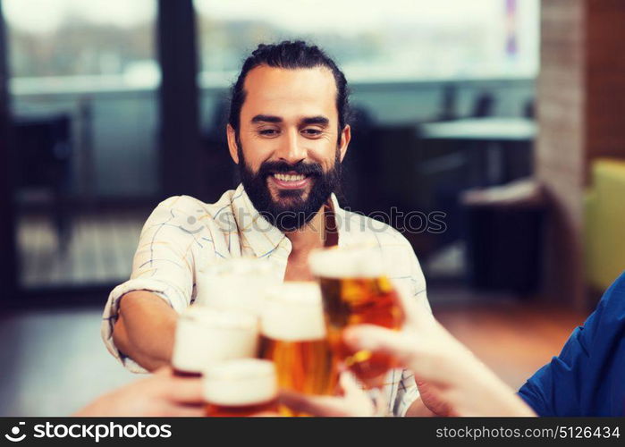 leisure, drinks, celebration, people and holidays concept - smiling man clinking beer glass with friends at restaurant. man clinking beer glass with friends at restaurant