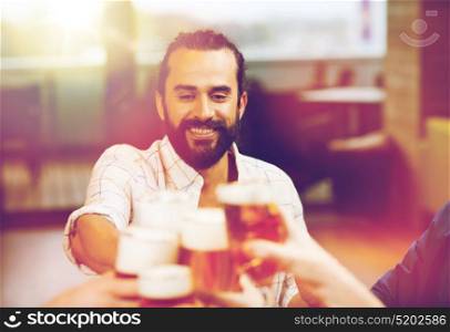 leisure, drinks, celebration, people and holidays concept - smiling man clinking beer glass with friends at restaurant. man clinking beer glass with friends at restaurant