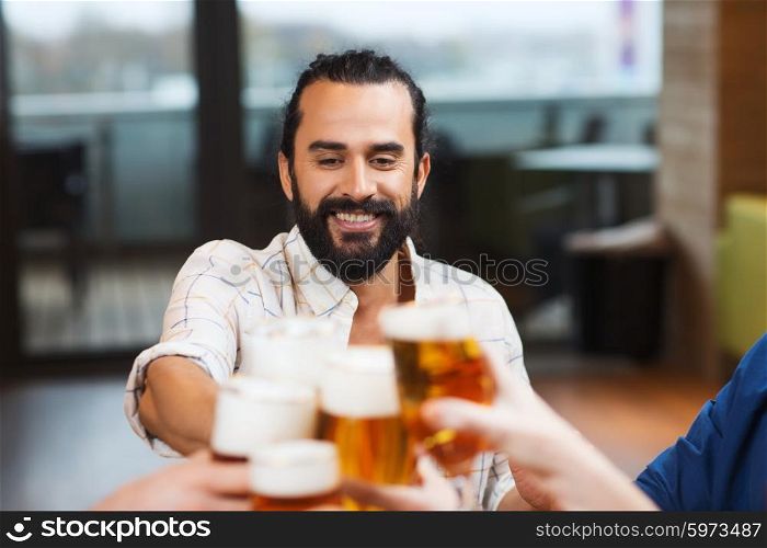 leisure, drinks, celebration, people and holidays concept - smiling man clinking beer glass with friends at restaurant