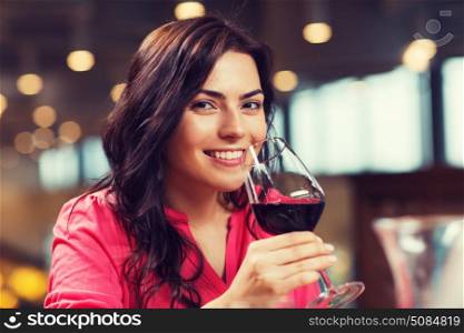 leisure, drinks, degustation, people and holidays concept - smiling woman drinking red wine at restaurant. smiling woman drinking red wine at restaurant. smiling woman drinking red wine at restaurant