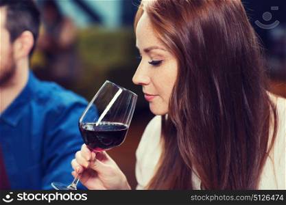 leisure, drinks, degustation, people and holidays concept - smiling woman drinking red wine at restaurant. smiling woman drinking red wine at restaurant