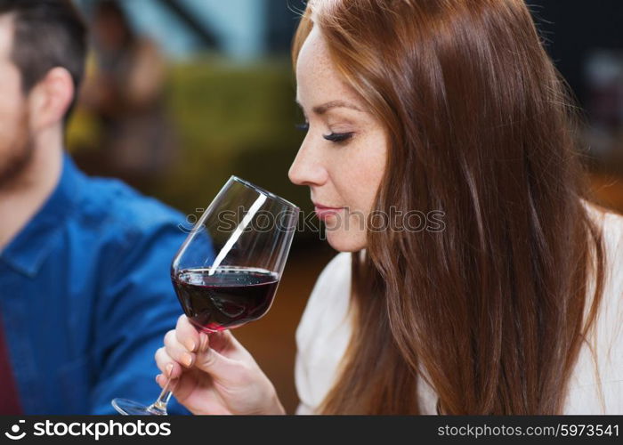 leisure, drinks, degustation, people and holidays concept - smiling woman drinking red wine at restaurant