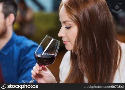leisure, drinks, degustation, people and holidays concept - smiling woman drinking red wine at restaurant