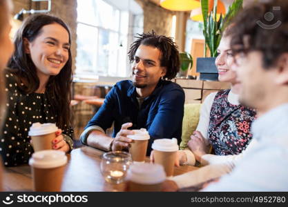 leisure, drinks, people and communication concept - happy friends drinking coffee from disposable paper cups at restaurant or cafe. happy friends drinking coffee at restaurant