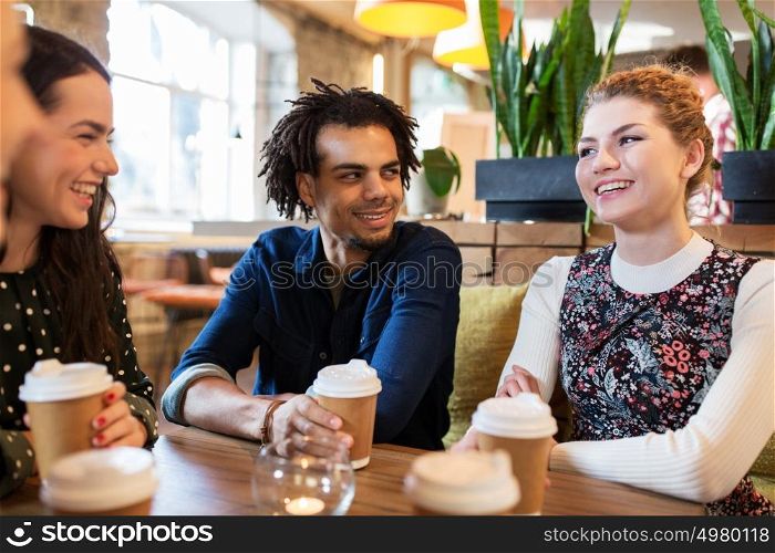 leisure, drinks, people and communication concept - happy friends drinking coffee from disposable paper cups at restaurant or cafe. happy friends drinking coffee at restaurant