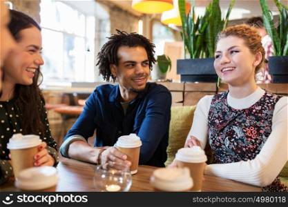 leisure, drinks, people and communication concept - happy friends drinking coffee from disposable paper cups at restaurant or cafe. happy friends drinking coffee at restaurant