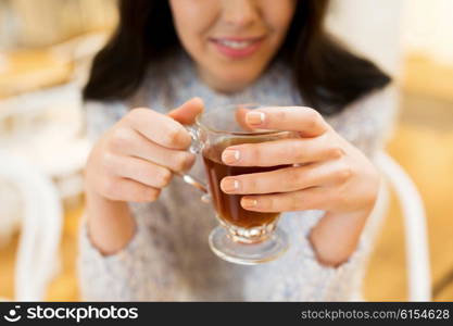 leisure, drinks, people and lifestyle concept - close up of happy young woman drinking tea at cafe
