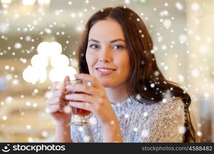 leisure, drinks, people and lifestyle concept - smiling young woman drinking tea at cafe