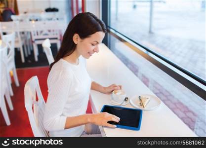 leisure, drinks, people, technology and lifestyle concept - smiling young woman with tablet pc computer drinking coffee at cafe