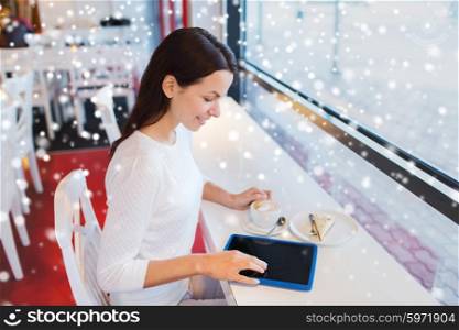 leisure, drinks, people, technology and lifestyle concept - smiling young woman with tablet pc computer drinking coffee at cafe over snow effect