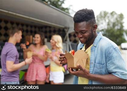 leisure, eating and people concept - happy african american man with wok and friends at food truck. happy man with wok and friends at food truck