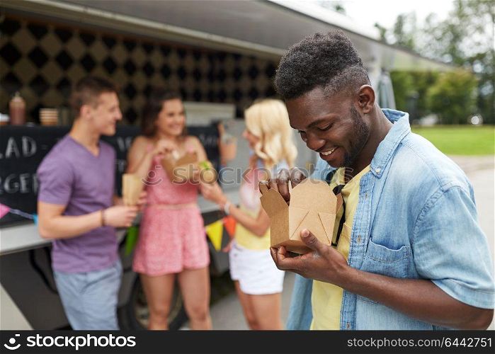 leisure, eating and people concept - happy african american man with wok and friends at food truck. happy man with wok and friends at food truck