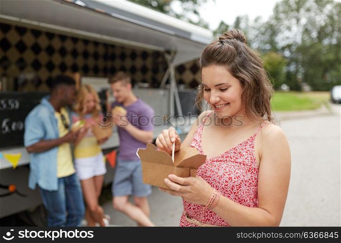 leisure, eating and people concept - happy young woman with wok and friends at food truck. happy woman with wok and friends at food truck