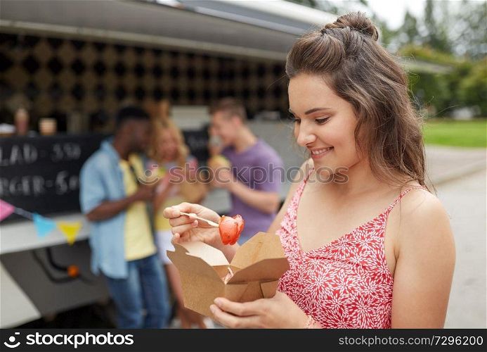 leisure, eating and people concept - happy young woman with wok and friends at food truck. happy woman with wok and friends at food truck