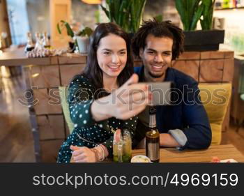 leisure, eating, food and drinks, people and holidays concept - happy couple with drinks at cafe or bar. happy couple taking selfie at cafe or bar