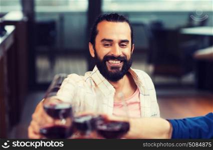 leisure, eating, food and drinks, people and holidays concept - happy man with friends clinking glasses of wine at restaurant. happy man clinking glass of wine at restaurant. happy man clinking glass of wine at restaurant
