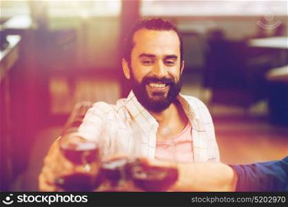 leisure, eating, food and drinks, people and holidays concept - happy man with friends clinking glasses of wine at restaurant. happy man clinking glass of wine at restaurant