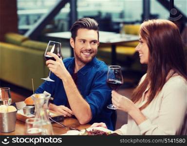 leisure, eating, food and drinks, people and holidays concept - smiling couple having dinner and drinking red wine at restaurant. couple dining and drinking wine at restaurant