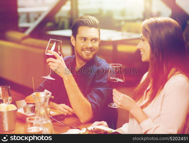 leisure, eating, food and drinks, people and holidays concept - smiling couple having dinner and drinking red wine at restaurant. couple dining and drinking wine at restaurant