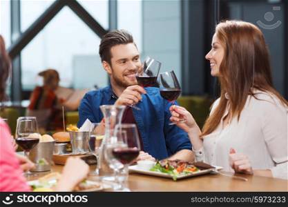leisure, eating, food and drinks, people and holidays concept - smiling couple having dinner and drinking red wine at restaurant