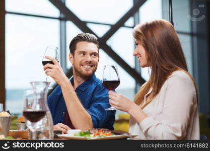 leisure, eating, food and drinks, people and holidays concept - smiling couple having dinner and drinking red wine at restaurant