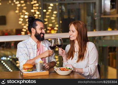 leisure, eating, food and drinks, people and holidays concept - smiling couple having dinner and drinking red wine at restaurant