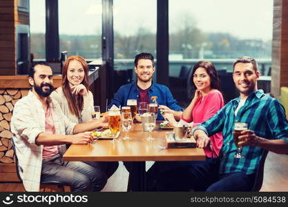 leisure, eating, food and drinks, people and holidays concept - smiling friends having dinner and drinking beer at restaurant or pub. friends dining and drinking beer at restaurant. friends dining and drinking beer at restaurant