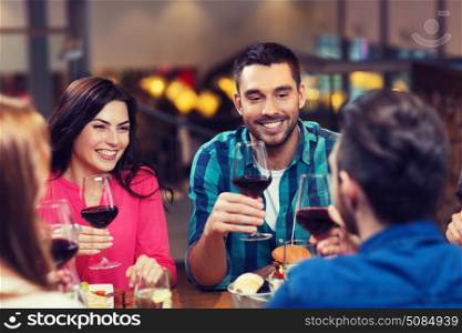 leisure, eating, food and drinks, people and holidays concept - smiling friends having dinner and drinking red wine at restaurant. friends dining and drinking wine at restaurant. friends dining and drinking wine at restaurant