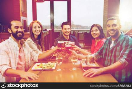 leisure, eating, food and drinks, people and holidays concept - smiling friends having dinner and drinking beer at restaurant or pub. friends dining and drinking beer at restaurant