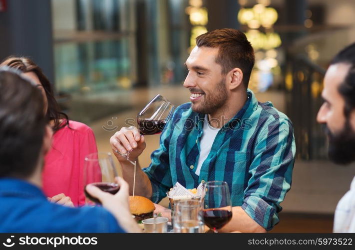 leisure, eating, food and drinks, people and holidays concept - smiling friends having dinner and drinking red wine at restaurant