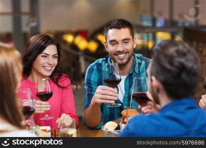 leisure, eating, food and drinks, people and holidays concept - smiling friends having dinner and drinking red wine at restaurant
