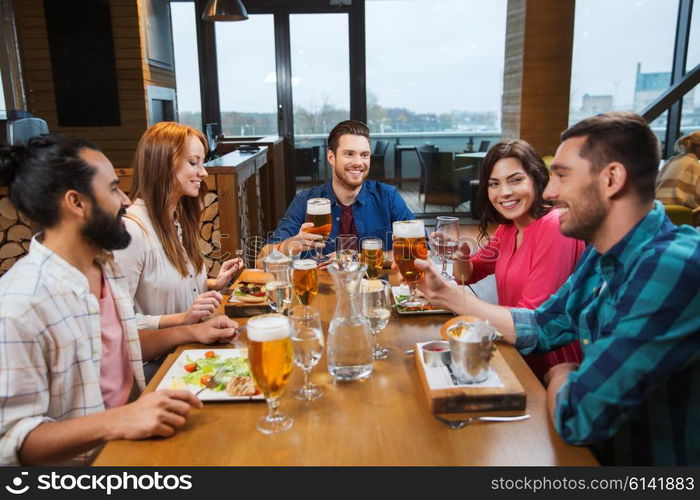 leisure, eating, food and drinks, people and holidays concept - smiling friends having dinner and drinking beer at restaurant or pub