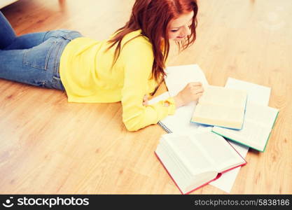 leisure, education and home concept - smiling teenage girl reading books on floor