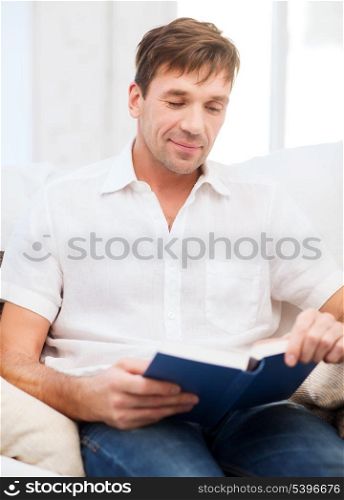 leisure, education and lifestyle concept - happy man with book at home