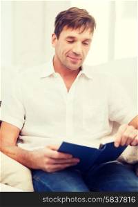 leisure, education and lifestyle concept - happy man with book at home